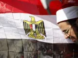 Un clérigo egipcio espera, al lado de una bandera de su país, un discurso televisado de Mohamed Morsi.