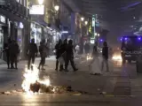 Varios fuegos arden en la calle de Preciados ante la mirada de los antidisturbios.