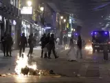 Varios fuegos arden en la calle de Preciados ante la mirada de los antidisturbios.