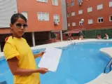 Cristina, socorrista de la piscina de una comunidad de vecinos de Torrej&oacute;n de Ardoz, mostrando el listado con los nombres de los propietarios que pueden ba&ntilde;arse y los que no.