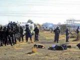 Unos policías inspeccionan los cuerpos de unos mineros muertos tras los tiroteos acontecidos cerca de una planta minera en Rustenburgo, Sudáfric.