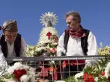 Varias personas ataviadas con el traje regional aragonés utilizan un ramo de flores para tejer el manto floral de la Virgen del Pilar.