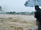Un hombre observa un río desbordado en una calle inundada en Puerto Príncipe, Haití, donde han muerto tres personas por los torrenciales aguaceros provocados por el huracán Sandy, de categoría dos, y que mantiene a todo el país en alerta máxima.