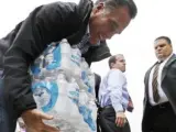 El candidato republicado Mitt Romney levanta botellas de agua en Ohio, donde ayudó en el suministro de provisiones a los afectados por Sandy.
