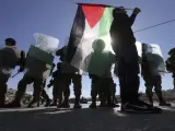Un joven sujeta una bandera palestina frente a una fila de soldados israel&iacute;es durante una protesta en el poblado de Al Masara, junto a Bel&eacute;n, en Cisjordania.