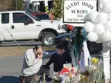 Un hombre y su hijo se acercan este sábado a las inmediaciones de la esuela infantil de Newtown donde este viernes fallecieron 20 niños y seis adultos como consecuencia de un tiroteo.