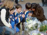 Varias personas se arrodillan junto a unas flores y velas colocadas junto a la escuela Sandy Hook, en Newtown, donde tuvo lugar la matanza perpetrada por Adam Lanza, un joven de 20 años.