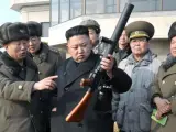 Fotografía facilitada por la agencia estatal KCNA que muestra al líder de Corea del Norte, Kim Jong-un (centro), inspeccionando un arma durante una maniobra con fuego de artillería en un lugar sin identificar y con fecha desconocida.