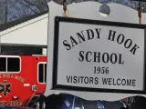 Coches de policía y bomberos delante de un letrero de la escuela Sandy Hook en Newtown (Connecticut, EE UU), donde ha tenido lugar el tiroteo.