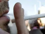 Un hombre fuma un cigarrillo en la calle.