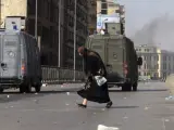 Una mujer cruza la calle junto a vehículos de las fuerzas de seguridad egipcias.