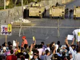 Decenas de simpatizantes del depuesto presidente egipcio Mohamed Mursi muestran pancartas y gritan consignas durante una protesta convocada por los Hermanos Musulmanes, frente a vehículos armados del Ejército.