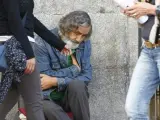 Un mendigo, sentado en una de las aceras de la Puerta del Sol, en Madrid.
