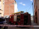 Un vehículo de los Mossos y otro de los Bomberos ante el edificio que se ha quemado (al fondo, a la izquierda) en Òdena.