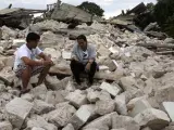 Dos hombres permanecen sentados entre los escombros de la iglesia de Nuestra Señora de la Luz, destruida por el terremoto de Bohol (Filipinas).