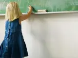 Una niña dibuja en una pizarra de su colegio.