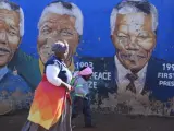 Una mujer y su hija pasan junto a un mural del expresidente sudafricano Nelson Mandela.