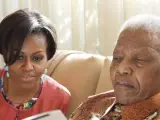 la primera dama estadounidense Michelle Obama (a la izquierda) y el expresidente Nelson Mandela (a la derecha) mientras revisan el libro "Nelson Mandela, por él mismo", en su casa en Johanesburgo, Sudáfrica, el 21 de junio de 2011
