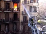 Un bombero intenta sofocar el incendio que ha calcinado un piso del Eixample de Barcelona, en el que ha fallecido un hombre de 78 años.