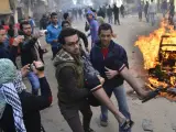 Dos personas trasladan a un hombre que resultó herido durante los disturbios en Giza, cerca de El Cairo (Egipto).