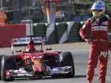 El piloto español Fernando Alonso espera en la pista la ayuda de la asistencia tras pararse el nuevo monoplaza F14T de la escudería Ferrari a la salida de la curva "Peluqui".