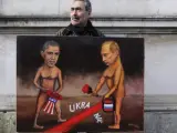 El artista Kaya Mar posa en Londres con un dibujo del presidente estadounidense y el presidente ruso en relación al conflicto ucraniano.