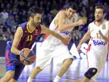 Juan Carlos Navarro, del FC Barcelona, controla un balón ante los jugadores del Olympiacos griego Giorgi Shermadini y Evangelos Mantzaris.