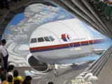Artistas del grupo artístico Guhit Visual Arts muestran una imagen del avión de Malaysia Airlines desaparecido en el patio del instituto Benigno Ninoy Aquino en Makati al sur de Manila (Filipinas).