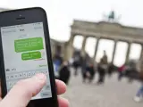 Una persona utiliza su teléfono móvil frente a la Puerta de Brandenburgo, en Berlín (Alemania).