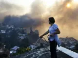 Una mujer humedece el tejado de su casa durante un incendio forestal en el cerro Ramaditas, en Valparaíso (Chile).