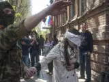 Un hombre con pasamontañas y ropa militar conduce a la activista y periodista ucraniana Imra Krat, retenida por manifestantes prorrusos.
