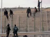 Algunos inmigrantes subidos a la valla de Melilla.