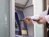 Un hombre saca dinero de un cajero automático.
