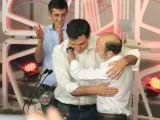 Rubalcaba abraza a Sánchez tras ganar las primarias del PSOE mientras Madina aplaude.