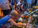Un niño enciende una vela entre ramos de flores en conmemoración de las víctimas del avión derribado de Malaysia Airlines al este de Ucrania.