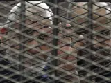 El líder de los Hermanos Musulmanes, Mohamed Badie, hace la señal de los cuatro dedos desde detrás de unas rejas, durante un juicio en El Cairo, Egipto.