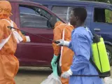Miembros de la Cruz Roja de Sierra Leona desinfectan el área después de recuperar los cuerpos de una mujer de 80 años y nieta que se cree murieron a causa del virus Ébola.