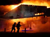 Unos bomberos intentan apagar el fuego en un establecimiento comercial de Ferguson (EE UU).