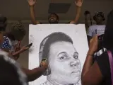 Un grupo de manifestantes sujetan un retrato de Michael Brown.