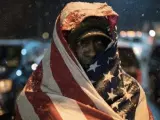 Un manifestante se cubre con una bandera de Estados Unidos en Ferguson.