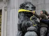 Fotografía facilitada por Greenpeace de sus activistas, amordazando uno de los leones que presiden la fachada del Congreso de los Diputados en Madrid, como acto de protesta pacífica contra el anteproyecto de Ley de Protección de la Seguridad Ciudadana (conocida popularmente como 'ley mordaza').