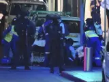 Miembros de los servicios médicos atienden a un herido junto a la cafetería tomada desde primeras horas de la mañana por un hombre armado en Sídney (Australia)