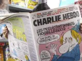 Una mujer lee el número del semanario satírico 'Charlie Hebdo', publicado antes del ataque terrorista, en un quiosco en París, Francia.