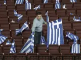 Un hombre coloca banderas griegas en un pabellón.