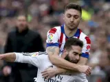 El defensa del Real Madrid Dani Carvajal cae ante el defensa brasileño del Atlético de Madrid Guilherme Siqueira.