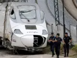 Efectivos de la policía custodian la locomotora del tren Alvia que descarriló en las inmediaciones de Santiago, antes de ser trasladada a Escravitude, en Padrón (A Coruña), a una zona custodiada por la Policía Nacional.