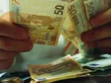 Un hombre recuenta billetes y monedas de euro.