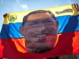 Un seguidor de Chávez sostiene una bandera venezonala con su cara en una manifestación en Caracas.