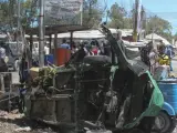 Miembros de las Fuerzas de Seguridad somalíes pasan junto a los restos de un vehículo delante de un edificio gubernamental atacado por yihadistas en Mogdiscio.