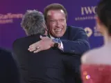 El actor estadounidense Arnold Schwarzenegger (d-detrás) da un abrazo al director francés Luc Besson (i-detrás) en la alfombra roja a su llegada a la quinta edición del Festival Internacional de Cine de Pekín.